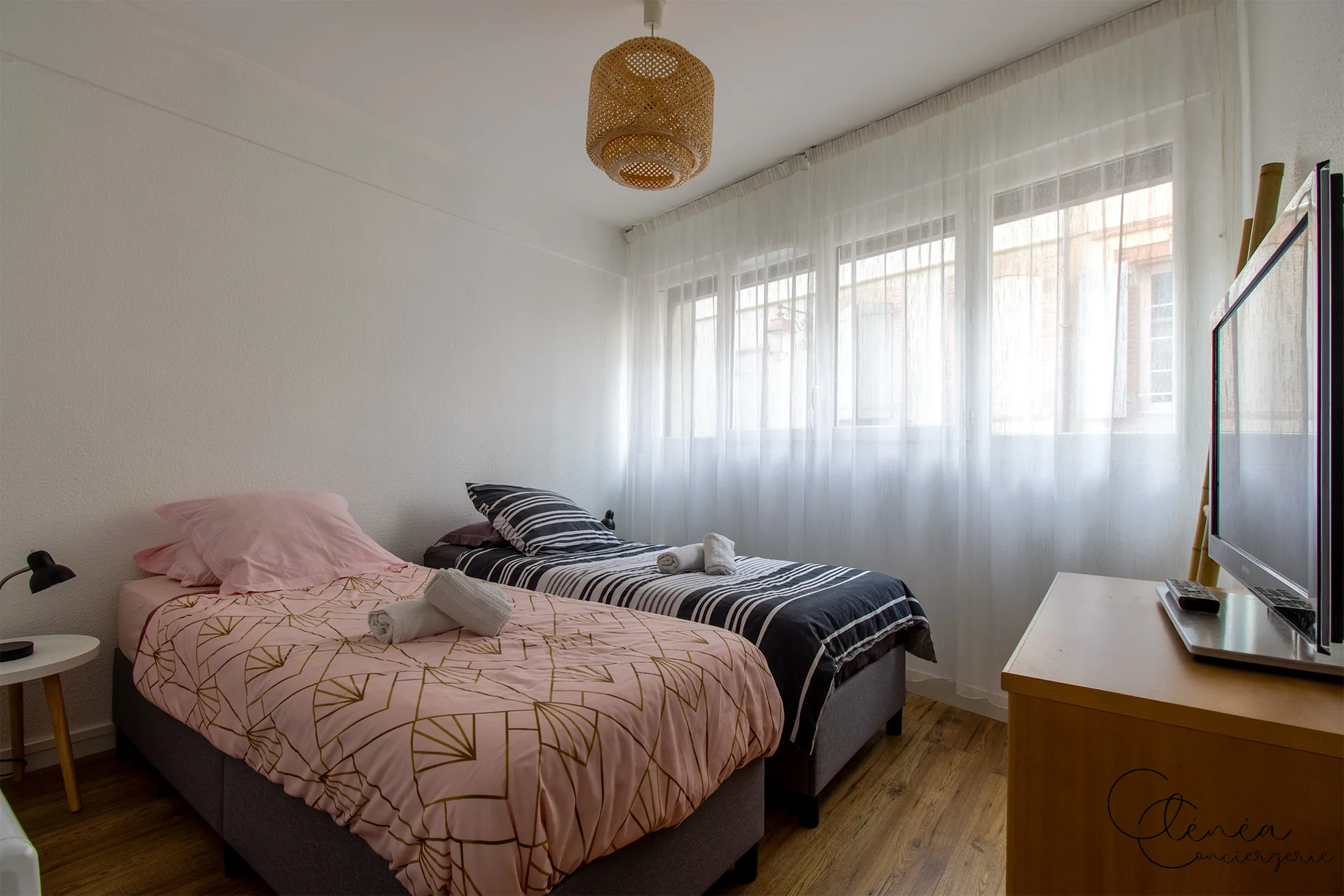 Au Cœur des Lices — Les deux lits simples de la seconde chambre, avec commode, télévision et large fenêtre voilée.