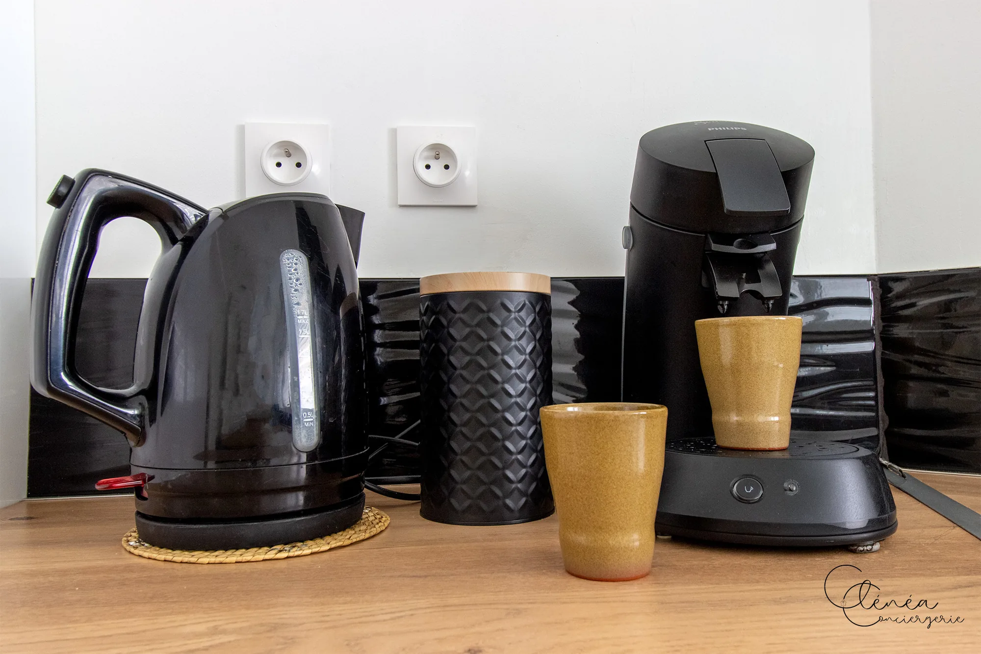 Au Cœur des Lices — Bouilloire, boîte à café et cafetière à dosettes posées sur le plan de travail de la cuisine.
