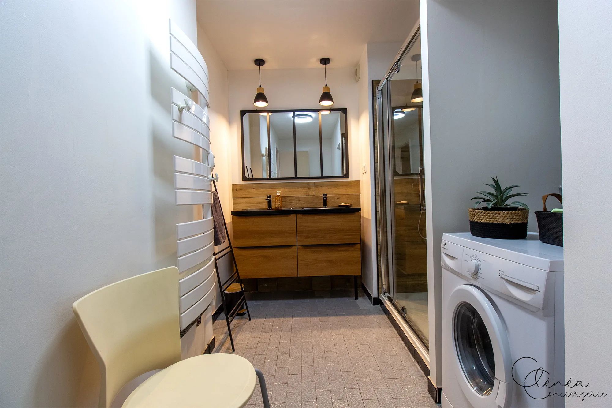 Au Cœur des Lices — La salle de bain vue depuis l'entrée, avec la machine à laver installée près de la douche.