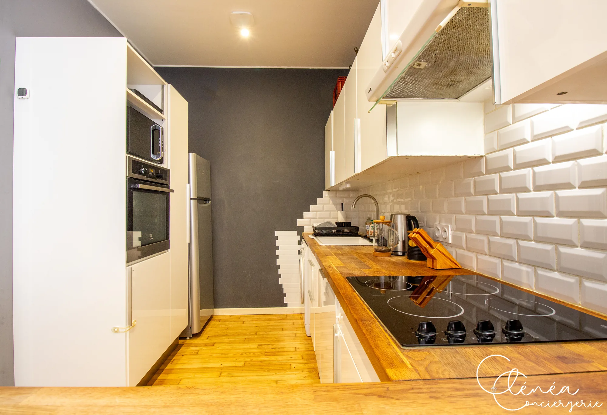 Chez Ludi et Pierre — Colonne de cuisine avec four et micro-ondes, réfrigérateur et plan de travail avec plaque vitrocéramique