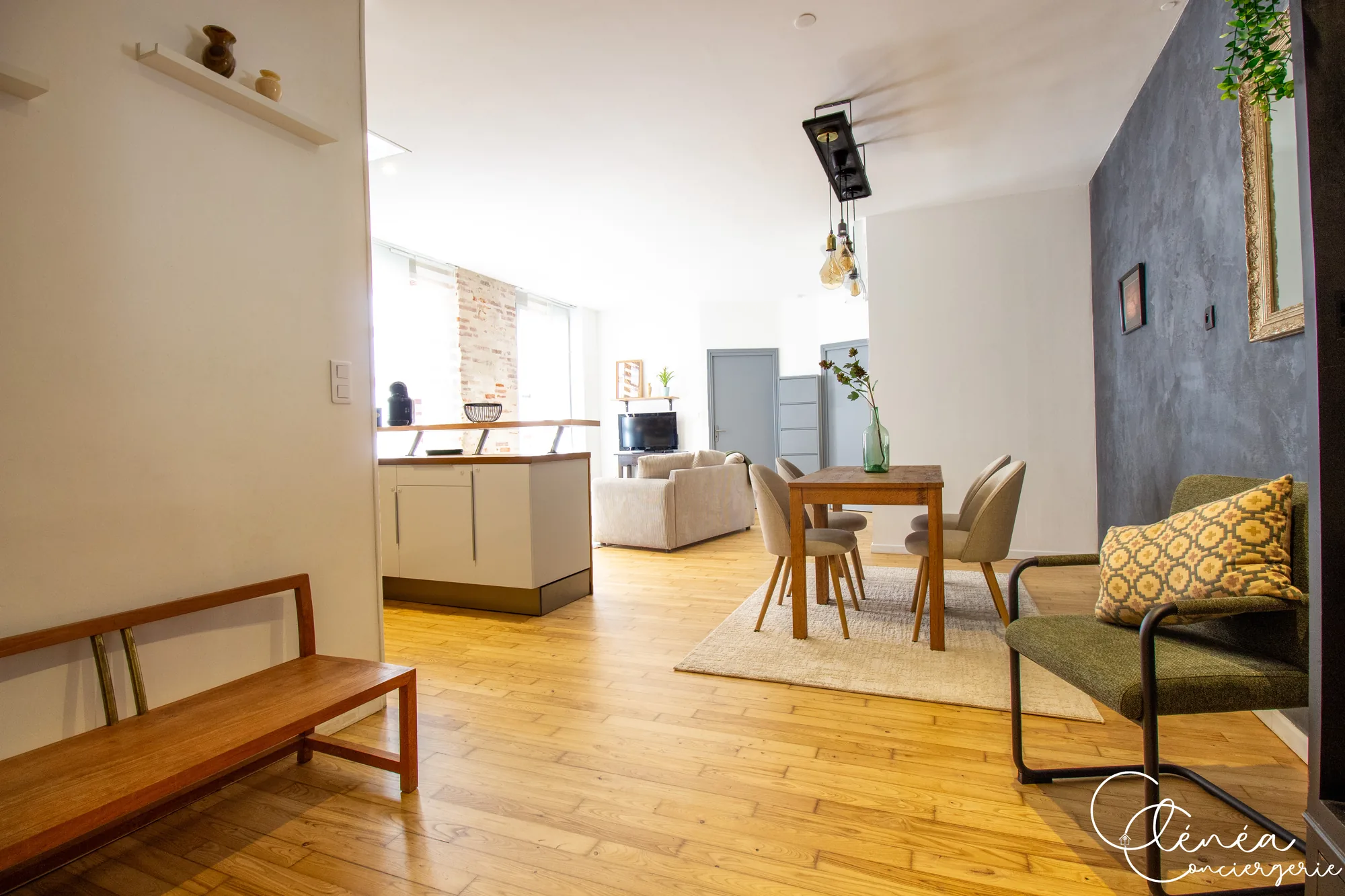 Chez Ludi et Pierre — Entrée avec banc en bois, ouverte sur le coin repas, la cuisine et le salon