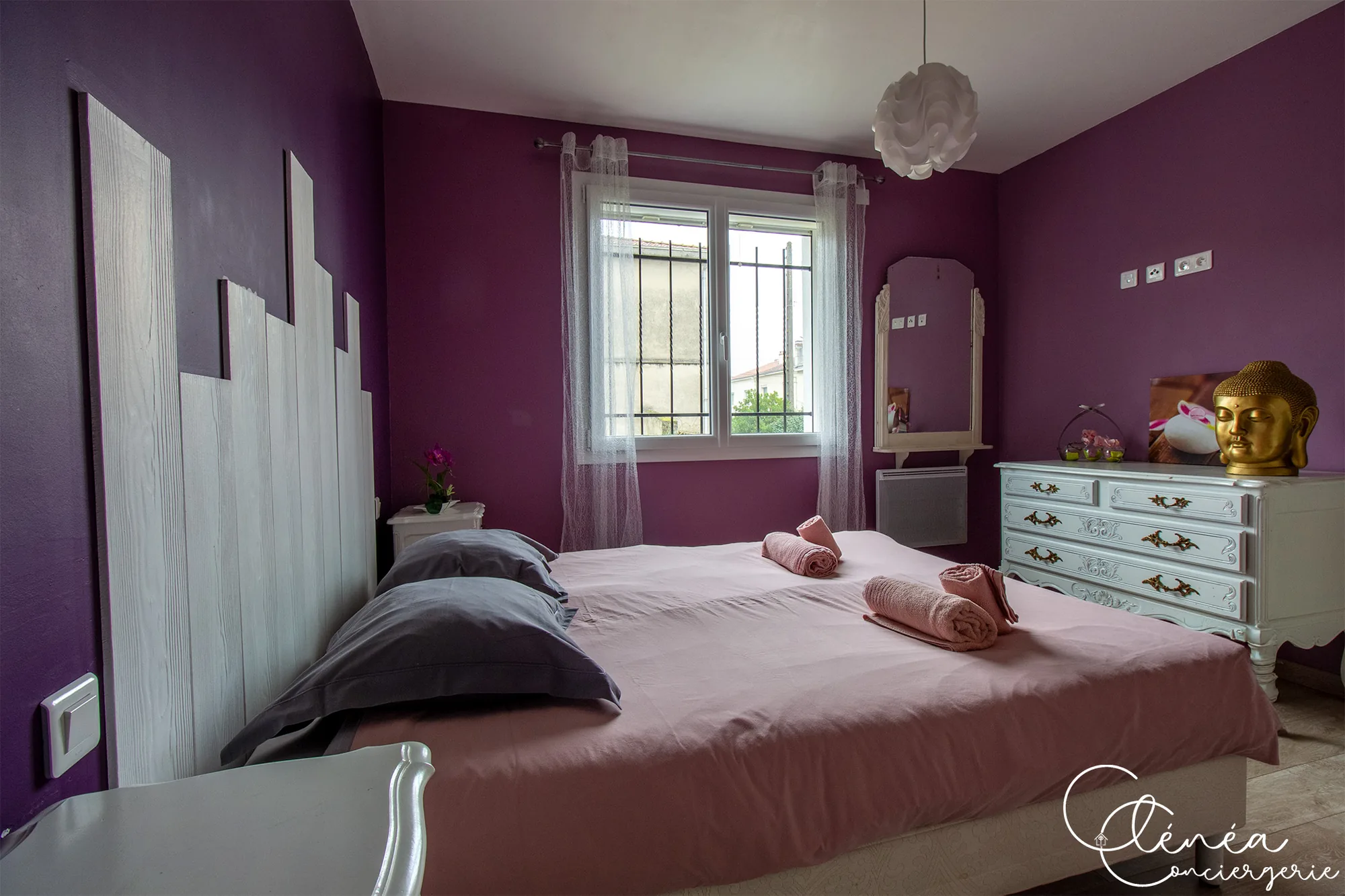 L’Escapade Albigeoise — Chambre violette vue depuis la tête de lit, avec fenêtre habillée de voilages et serviettes posées sur le lit