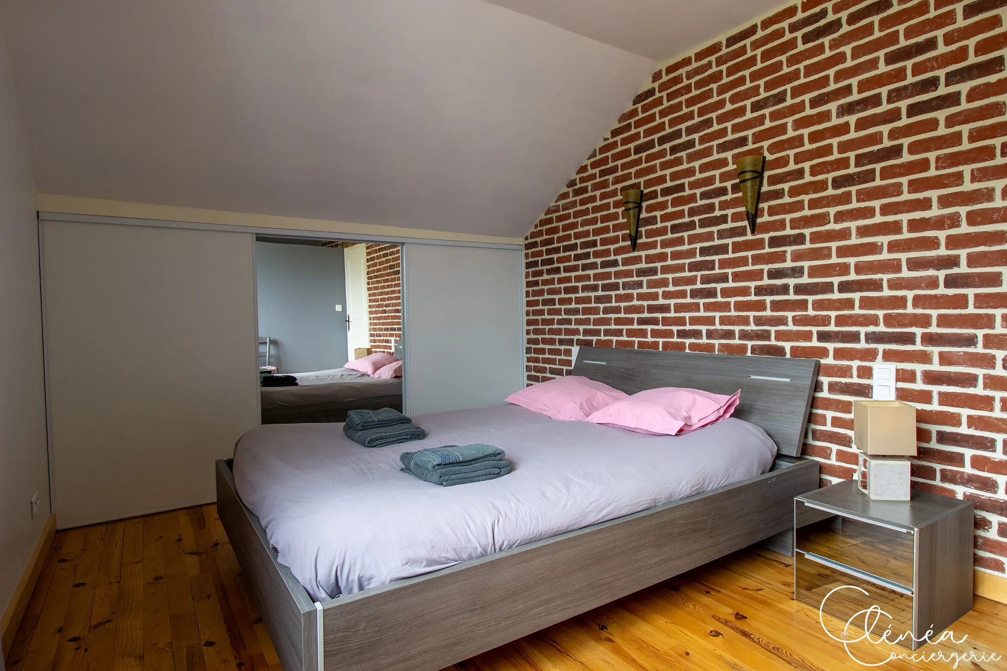 L’Escapade Albigeoise — Chambre à l’étage avec lit double adossé à un mur de briques, parquet ancien et dressing à portes coulissantes