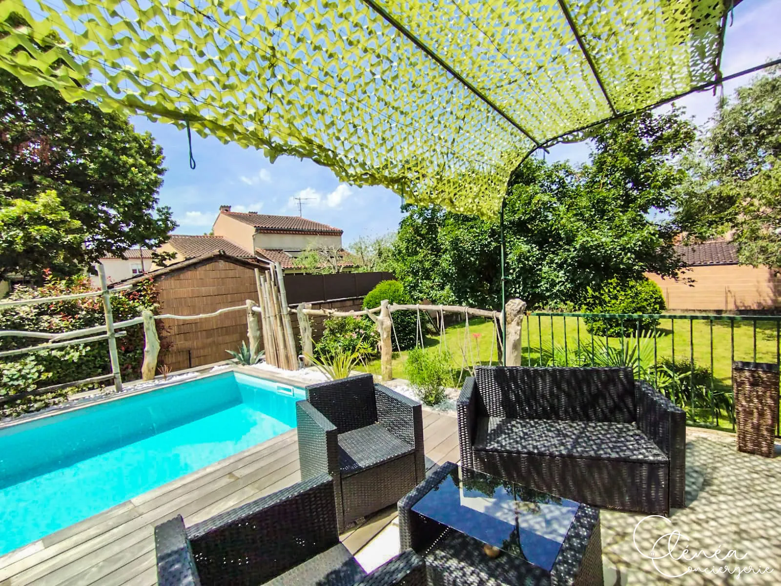L’Escapade Albigeoise — Fauteuils et canapé en résine tressée disposés au bord de la piscine, sous le voile d’ombrage