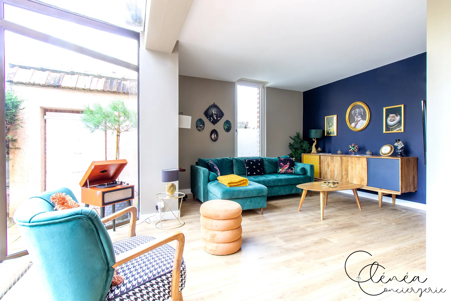 Évasion — Salon avec canapé d'angle vert, mur bleu nuit et buffet en bois