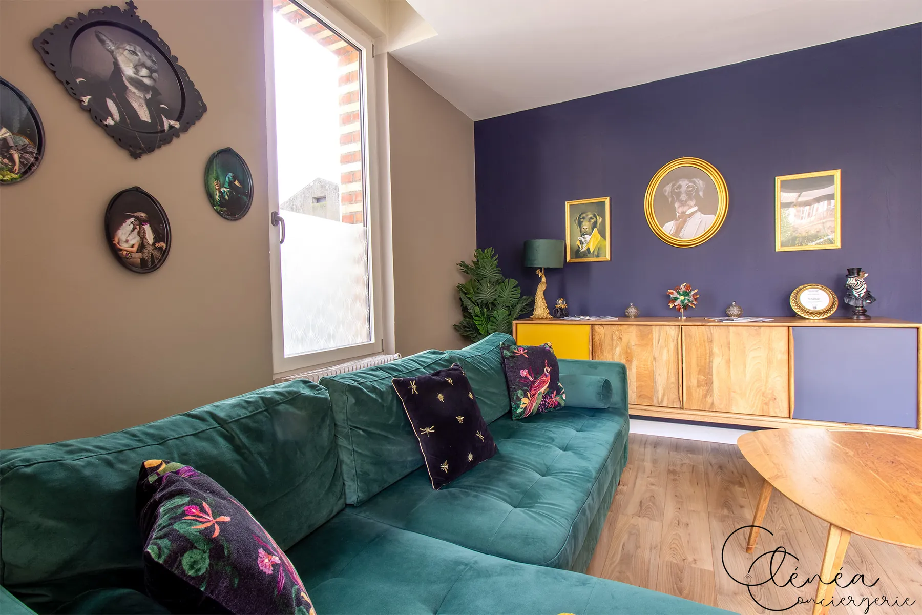 Évasion — Salon meublé d'un buffet en bois et d'une collection de cadres au mur