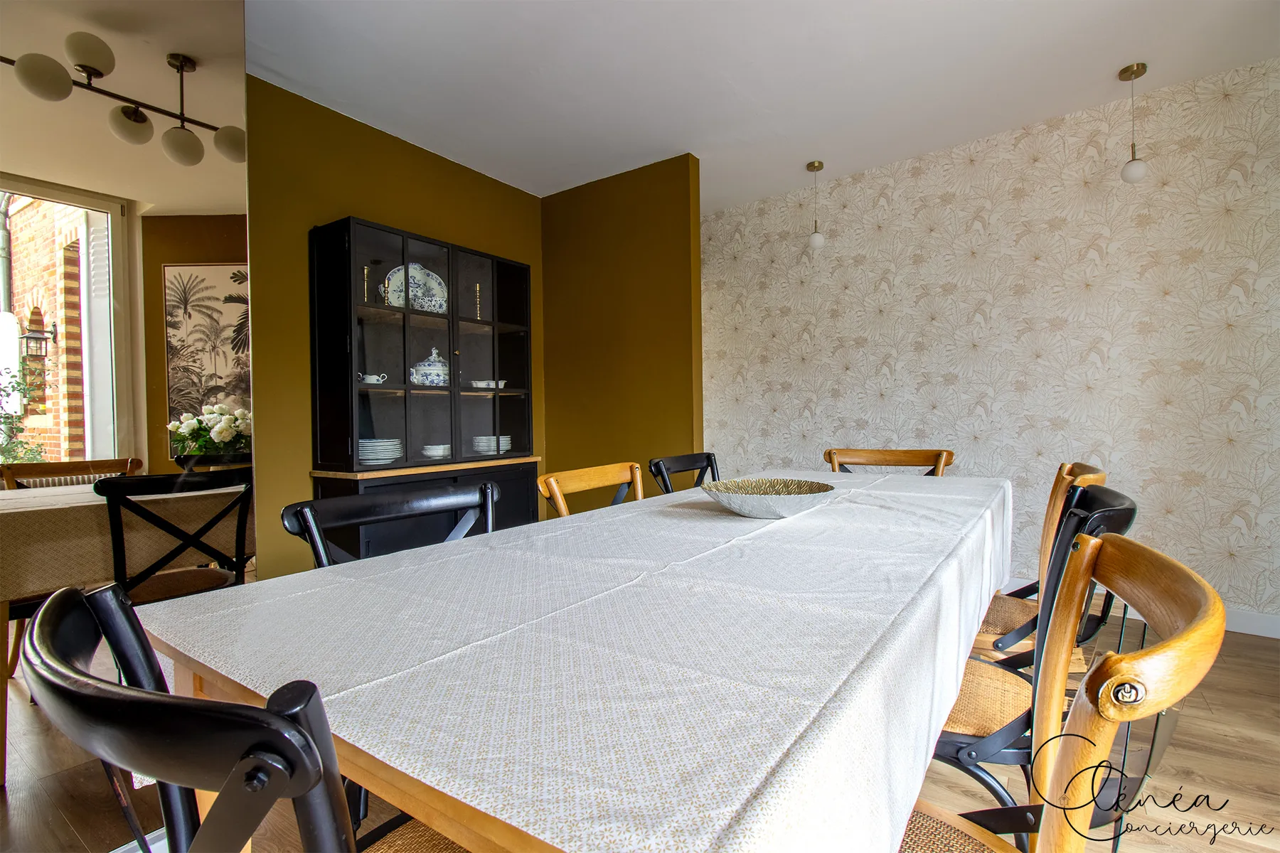 Évasion — Grande table à manger dressée, devant un vaisselier vitré