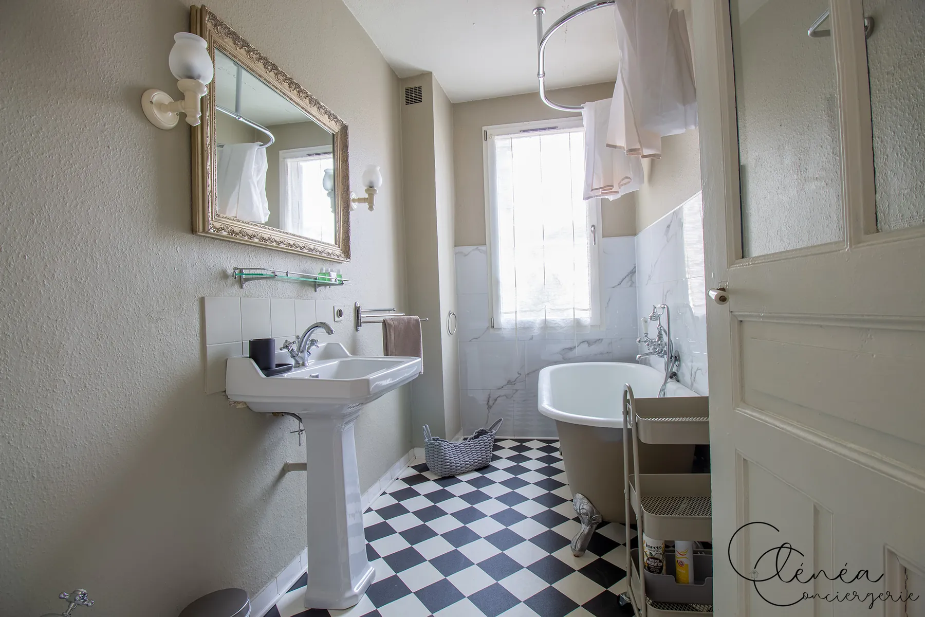 Évasion — Salle d'eau au sol en damier noir et blanc, avec lavabo et baignoire