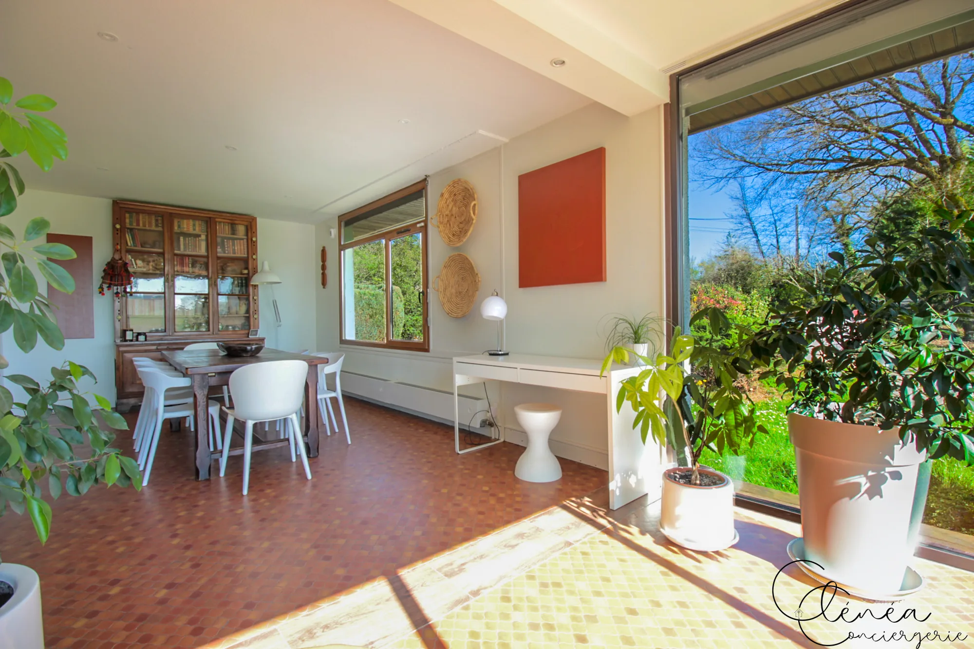 GreenOak — Bureau blanc et tabouret installés le long du mur, près d’une baie vitrée ouverte sur le jardin