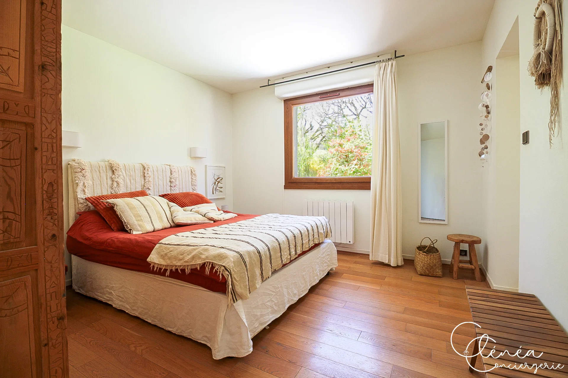 GreenOak — Chambre au lit double habillé de rouge et de blanc, tête de lit en laine tissée et porte en bois sculpté