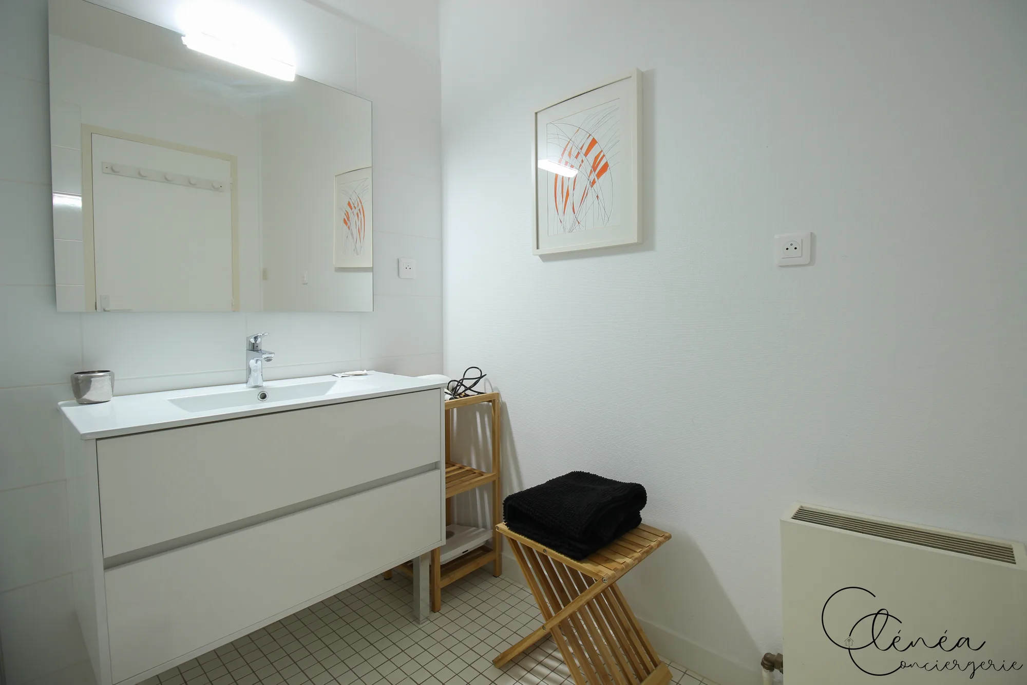 GreenOak — Salle d’eau blanche avec meuble vasque, miroir, tabouret et serviettes pliées