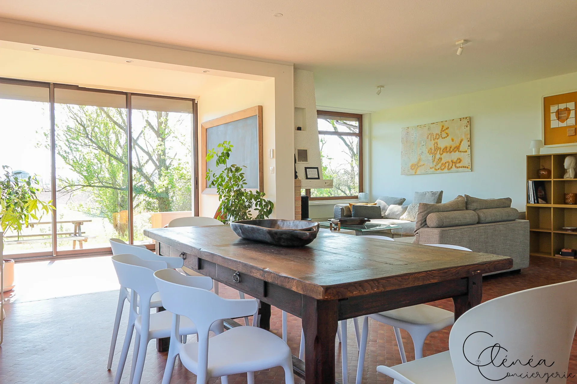 GreenOak — Table de repas devant une baie vitrée, avec le salon et ses canapés gris à l’arrière-plan