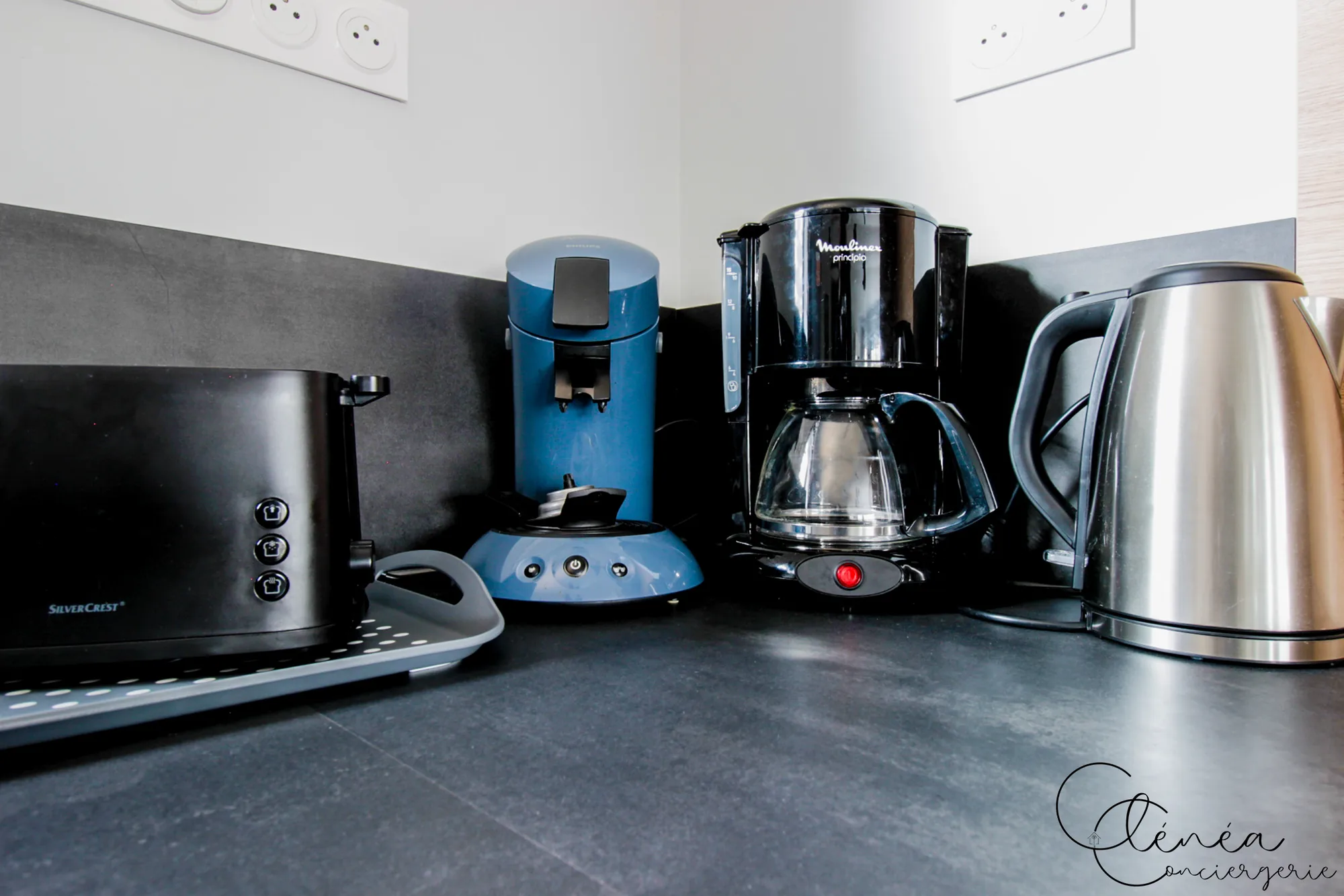 La Vigne — Grille-pain, machine à café Senseo, cafetière filtre et bouilloire posés sur le plan de travail.