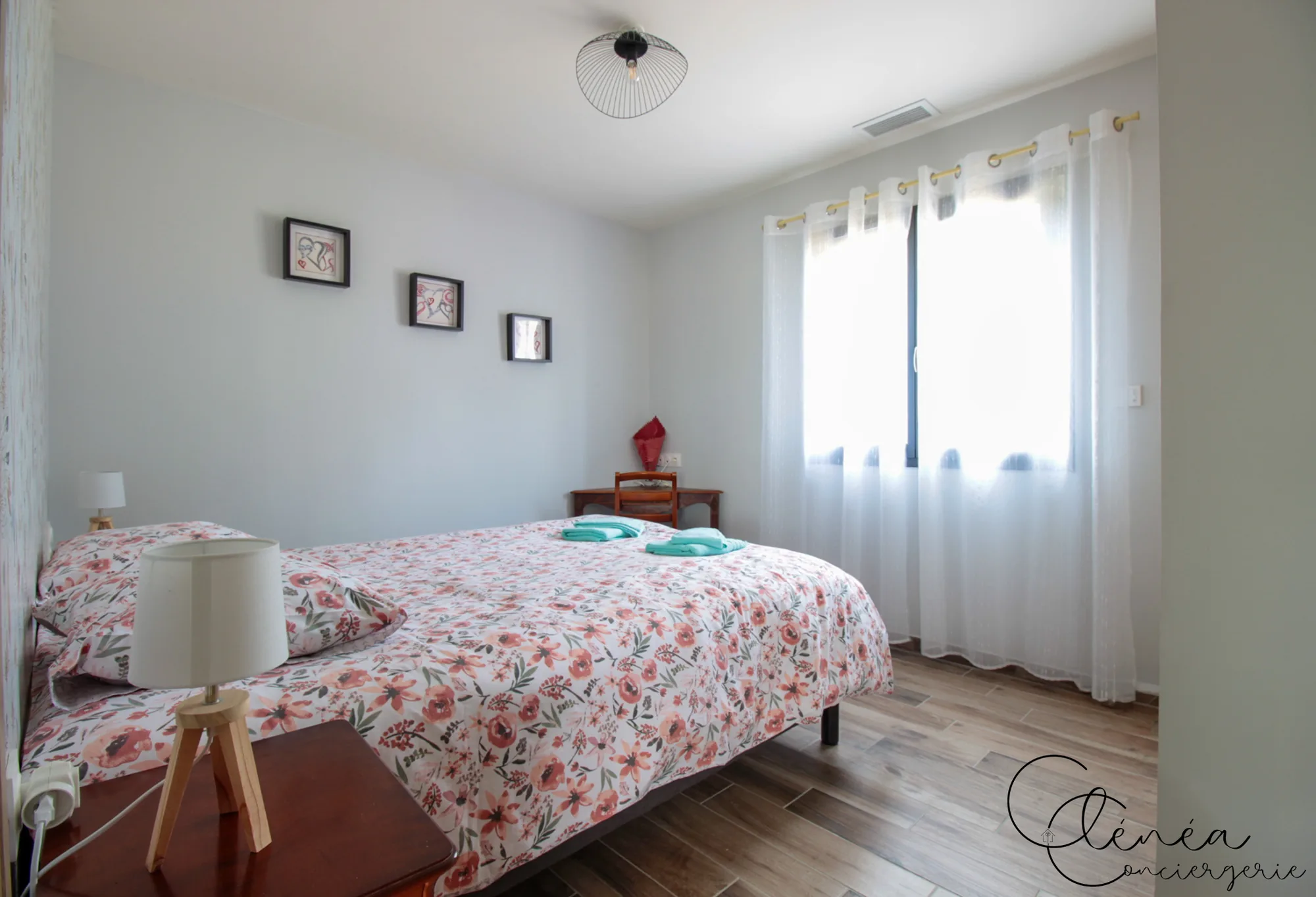 La Vigne — Chambre au lit double fleuri, avec un petit bureau en bois et sa chaise près de la fenêtre.