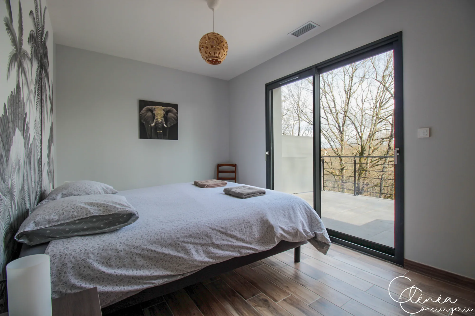 La Vigne — Chambre au mur décoré de palmiers, avec lit double et baie vitrée donnant sur la terrasse.