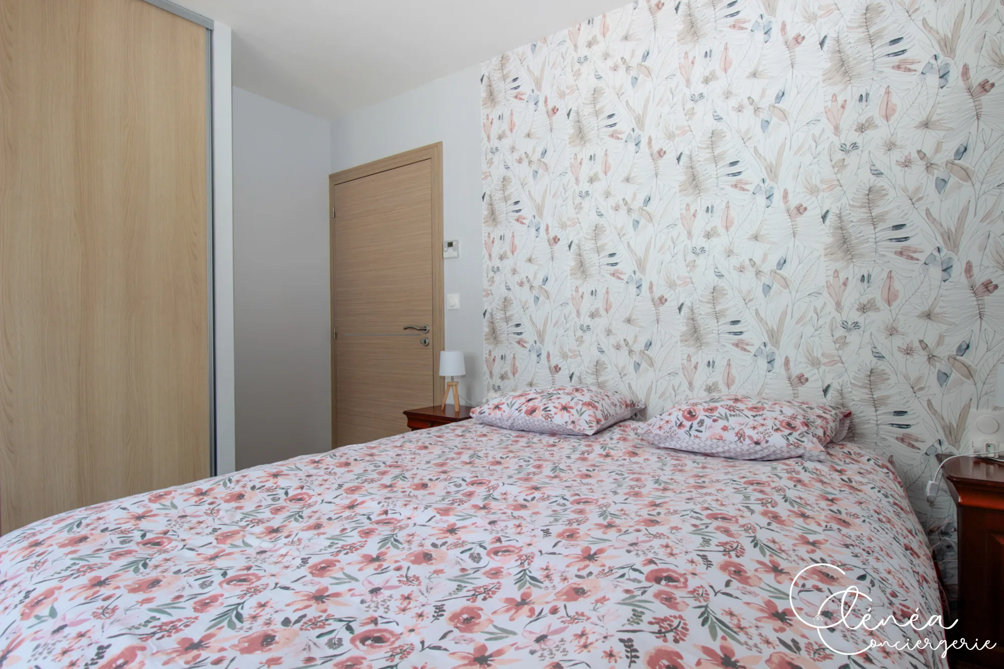 La Vigne — Lit double de la chambre 2 devant le papier peint floral, avec placard coulissant.