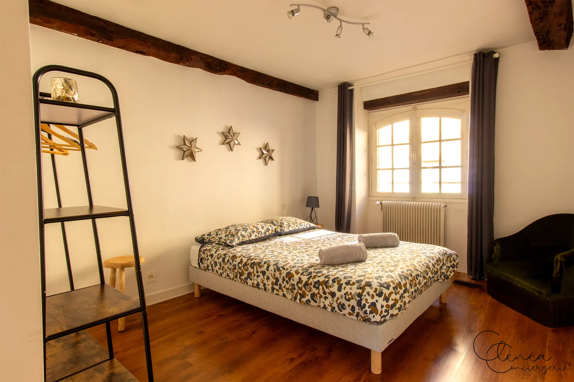 Le Quinze — Chambre avec lit double, parquet, fenêtre cintrée et petit fauteuil vert
