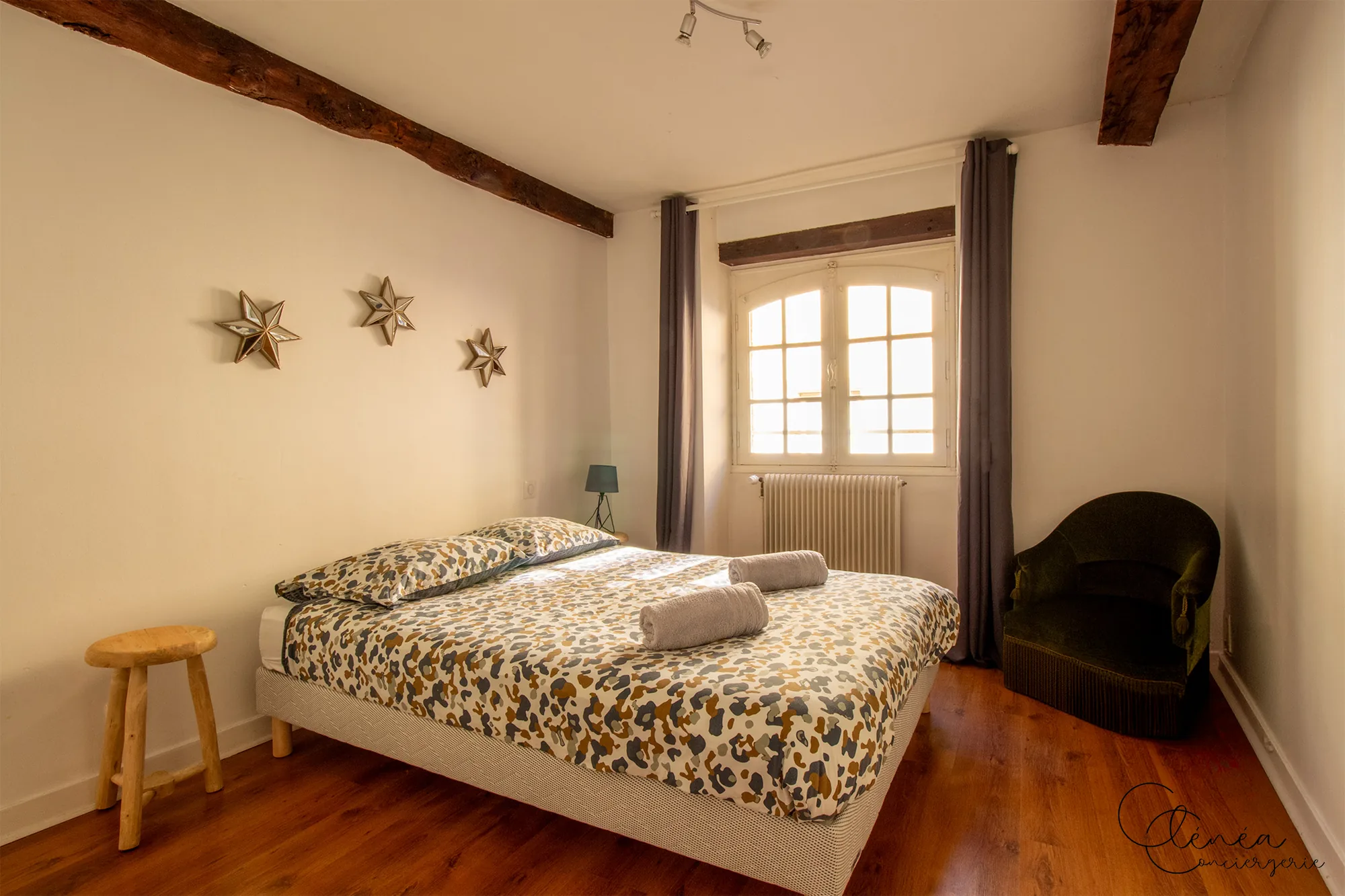 Le Quinze — Vue d’ensemble de la chambre : lit double, étoiles décoratives au mur, fenêtre et fauteuil