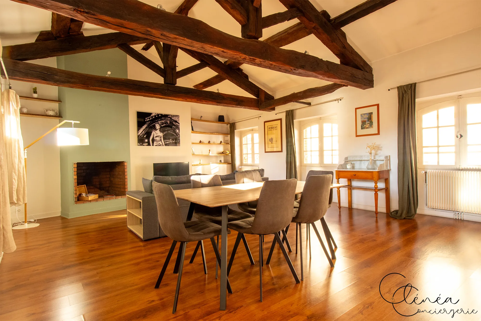 Le Quinze — Séjour lumineux réunissant la table de repas et le coin salon sous une haute charpente en bois