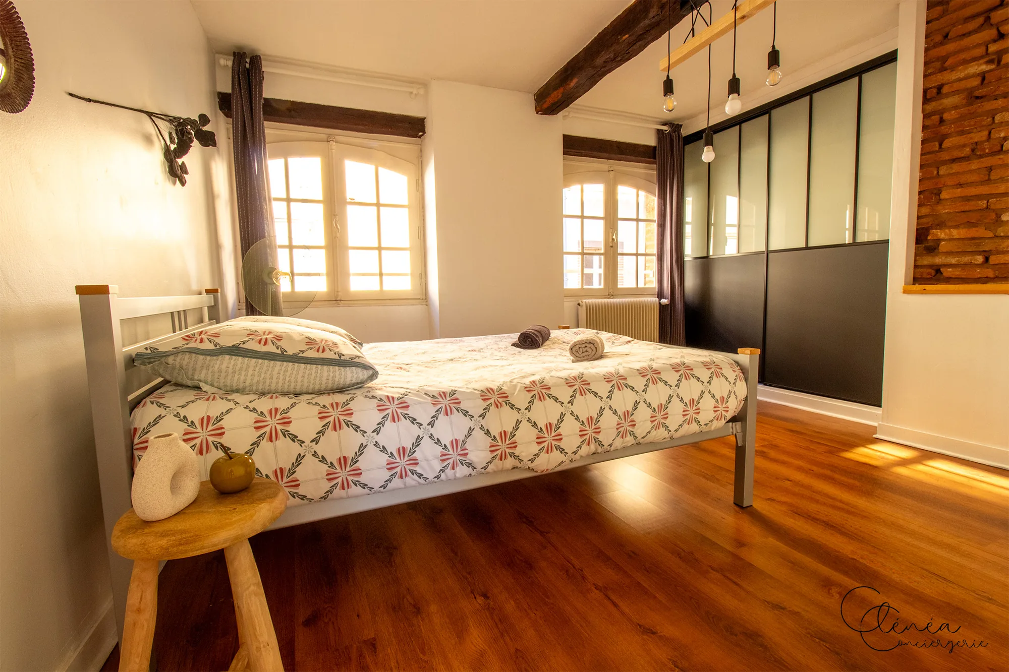 Le Quinze — Chambre avec lit double, deux fenêtres, verrière d’atelier et pan de mur en briques