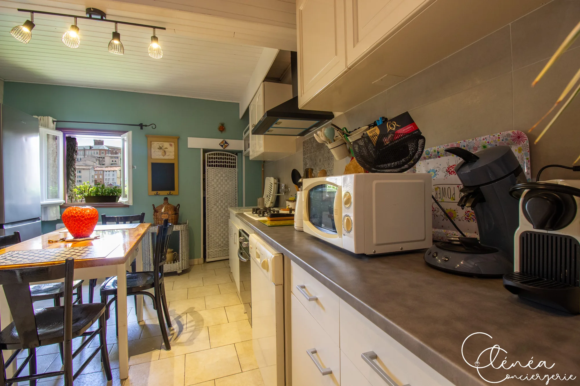 Saudade d’Albi — Plan de travail de la cuisine avec micro-ondes, machines à café Nespresso et Senseo, lave-vaisselle et coin repas en enfilade.