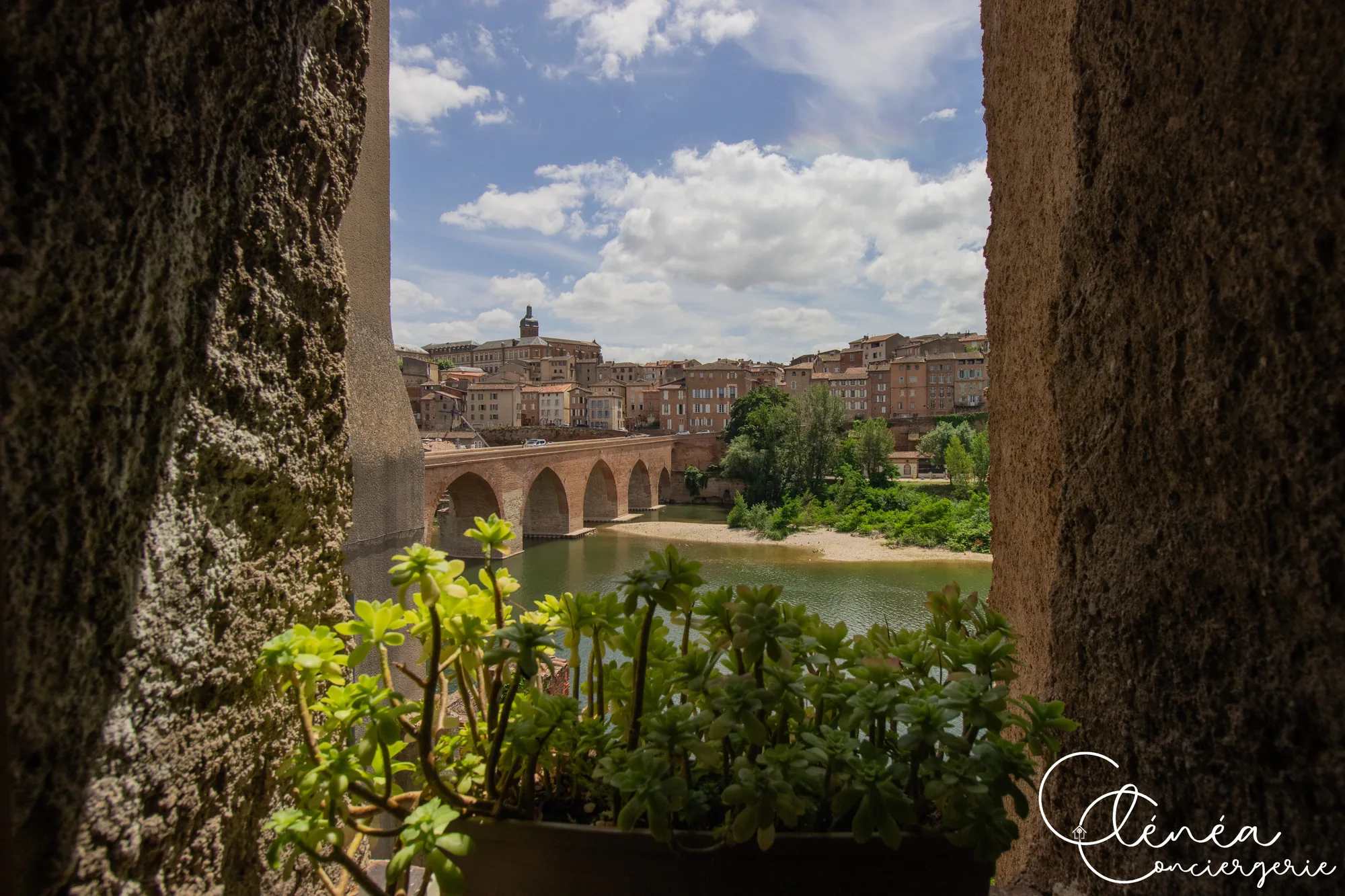 Saudade d’Albi — Le Pont Vieux et les façades du centre d’Albi vus à travers une ouverture en pierre, au-dessus du Tarn.