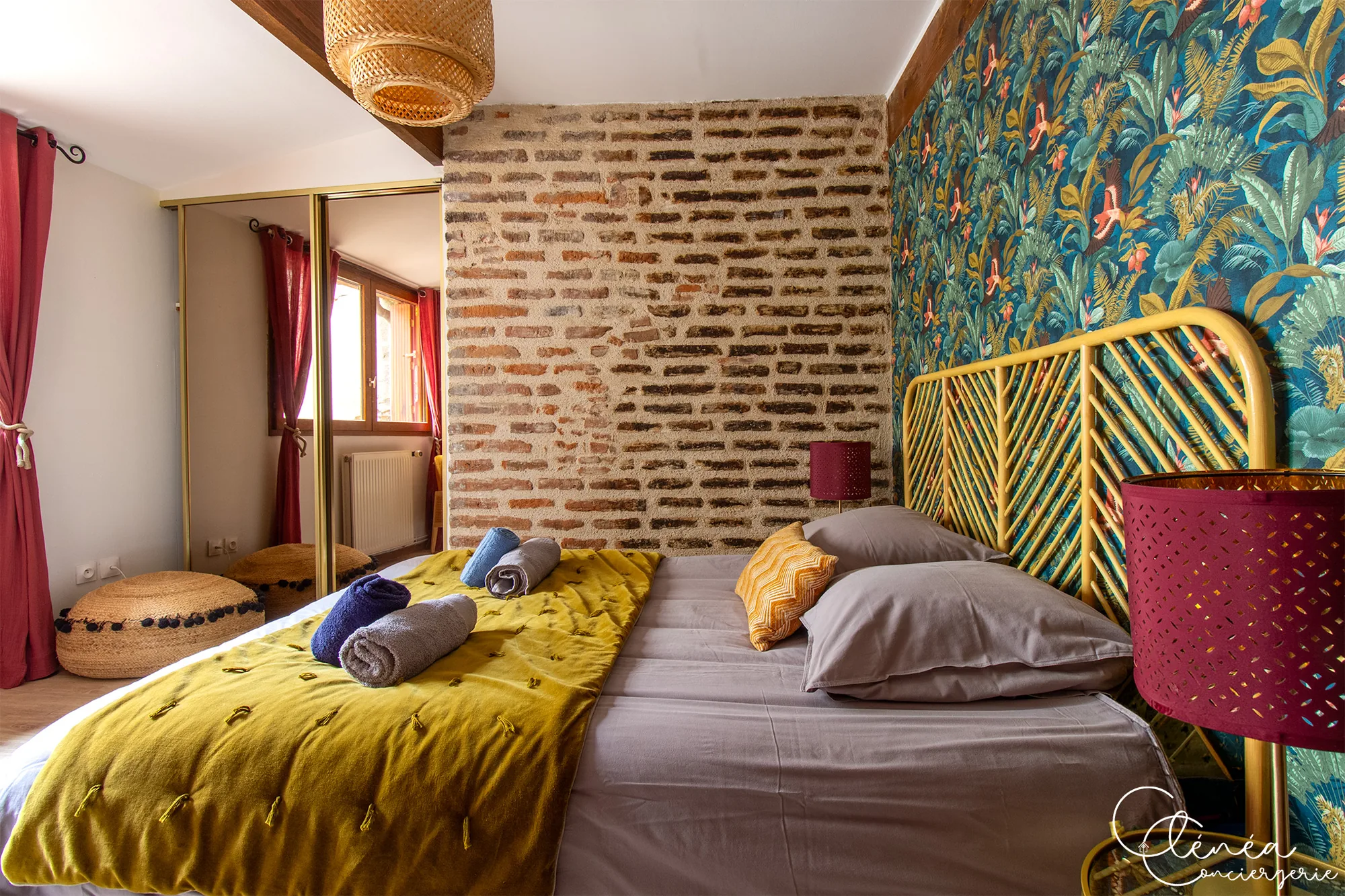The Nest — Chambre avec lit double, mur de briques apparentes et placard à portes miroir reflétant la fenêtre.