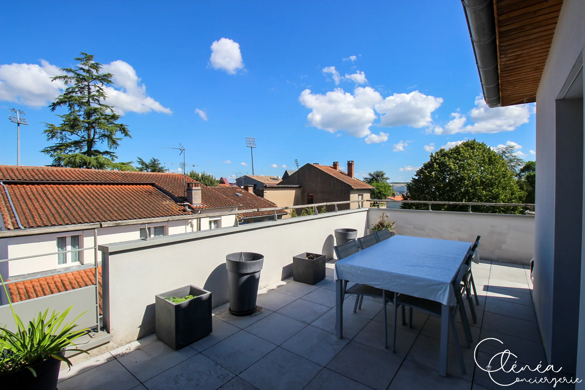 Urban Jungle — Grande table de terrasse et ses chaises, avec une vue dégagée sur les toits d’Albi.