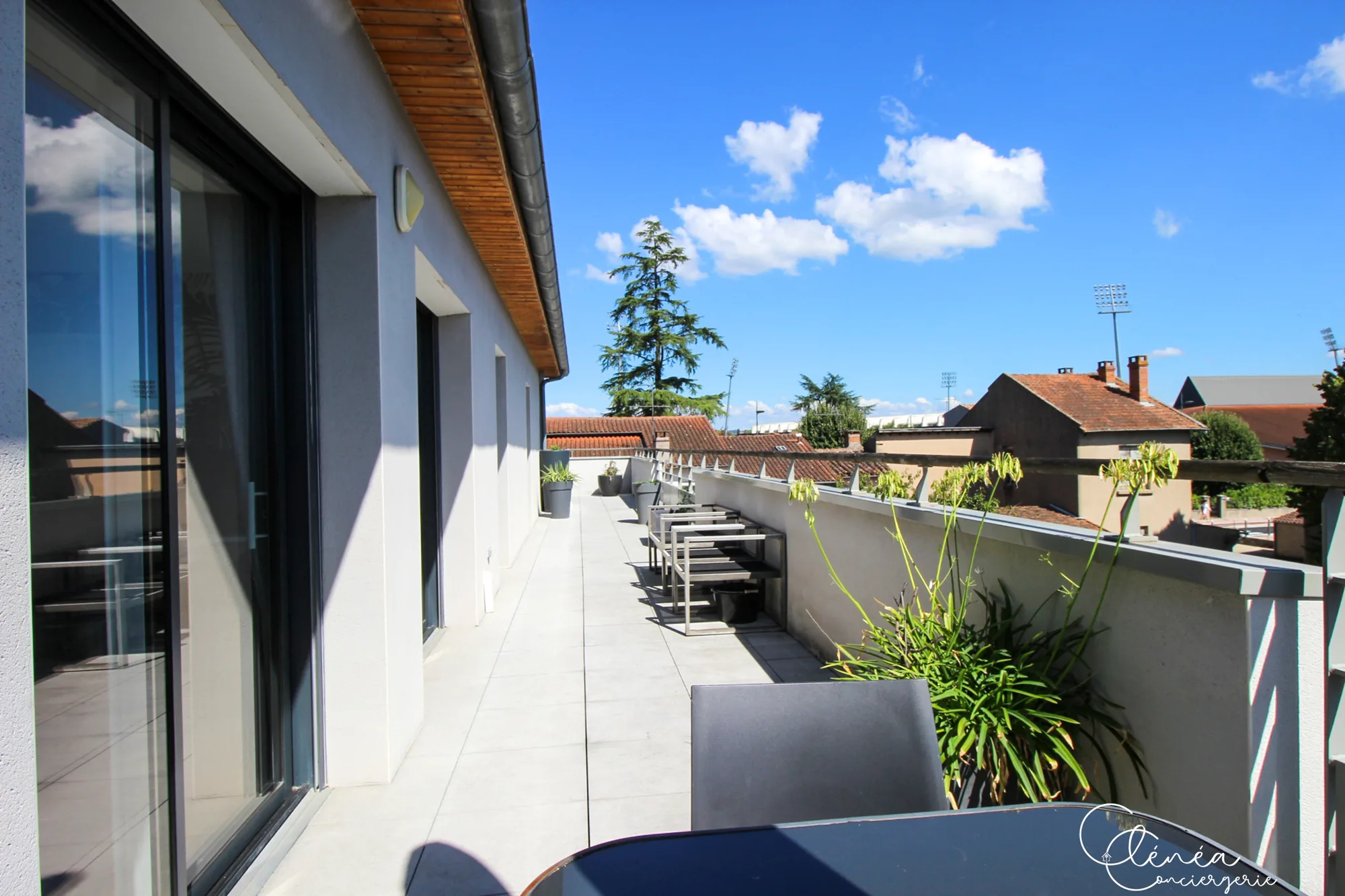 Urban Jungle — Terrasse longeant les baies vitrées de l’appartement, avec plantes en pot et mobilier de jardin.