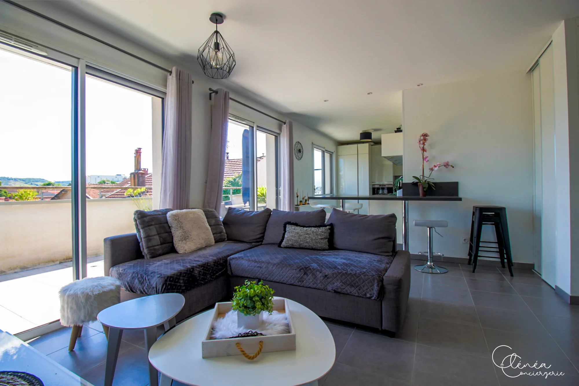 Urban Jungle — Séjour ouvert sur la cuisine, avec canapé d’angle et grandes baies vitrées donnant sur la terrasse.