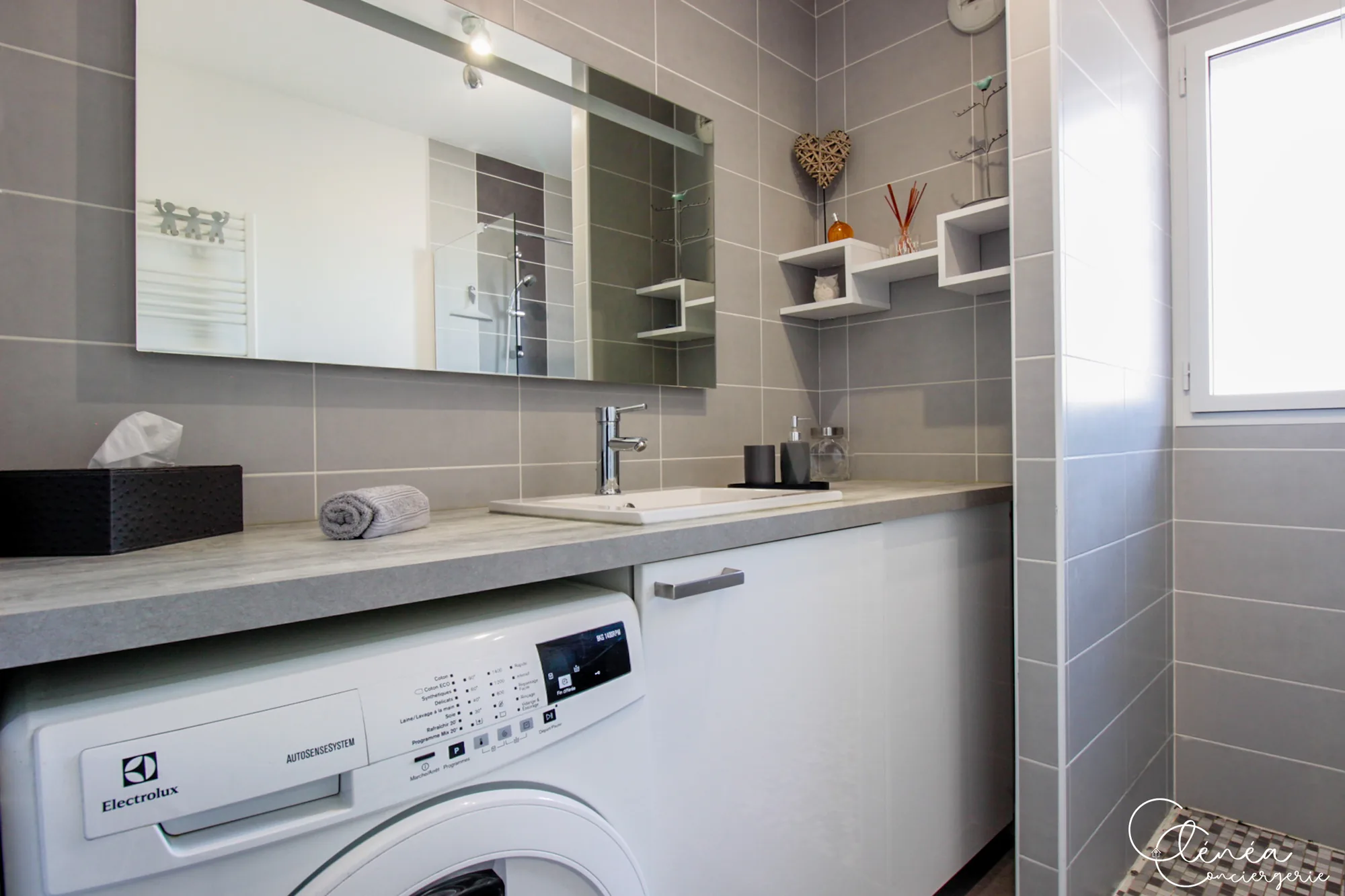 Urban Jungle — Meuble vasque avec grand miroir et lave-linge intégré sous le plan de la salle de bain.
