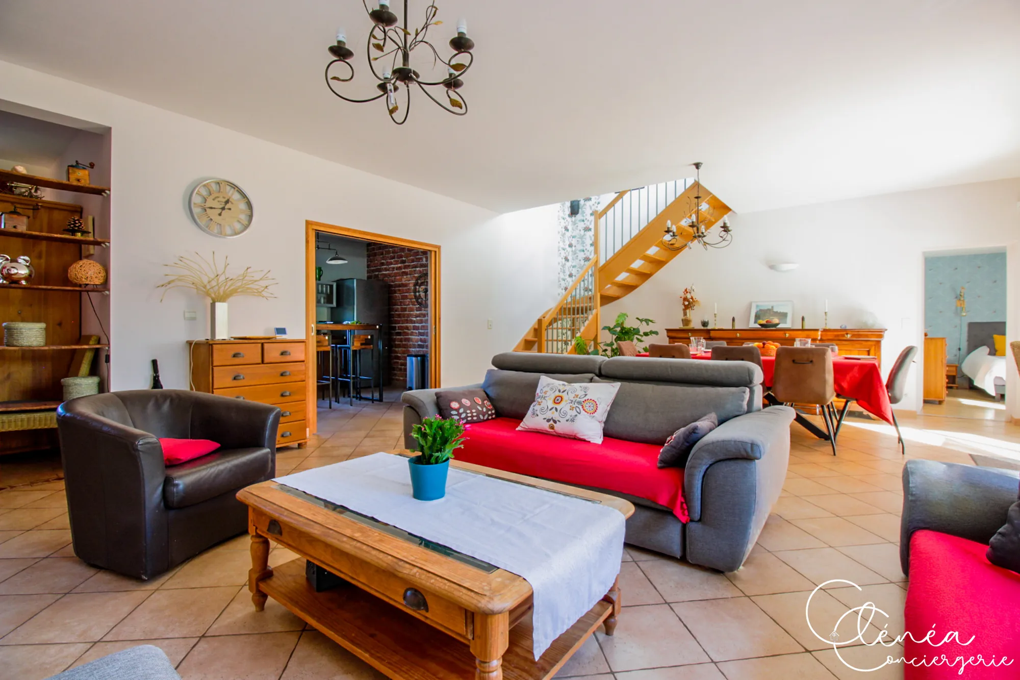 Villa Chanoine — La pièce de vie avec le salon au premier plan, l'escalier en bois et la salle à manger en arrière-plan.