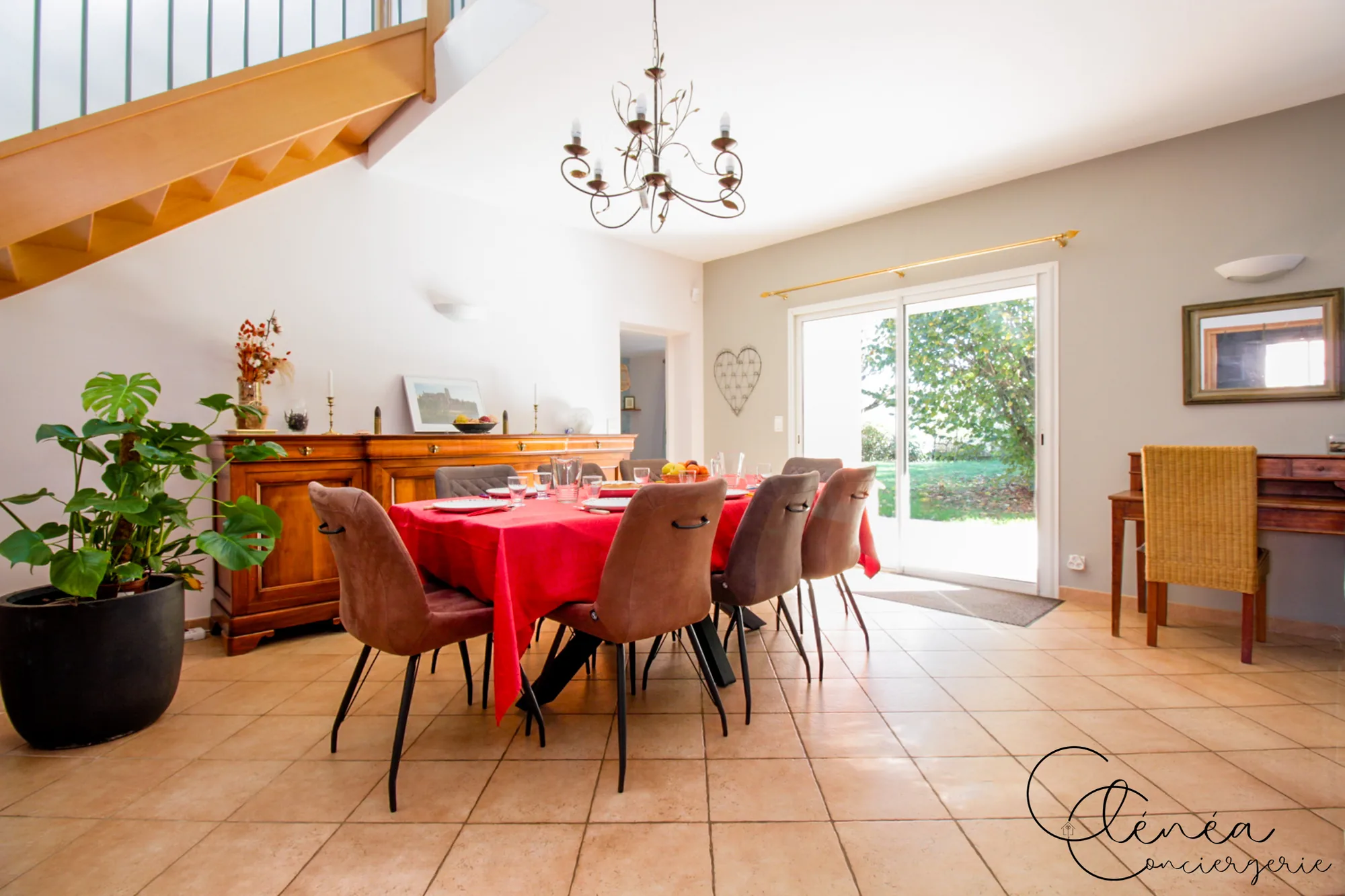 Villa Chanoine — La salle à manger et sa grande table dressée pour huit, devant la baie vitrée ouverte sur le jardin.