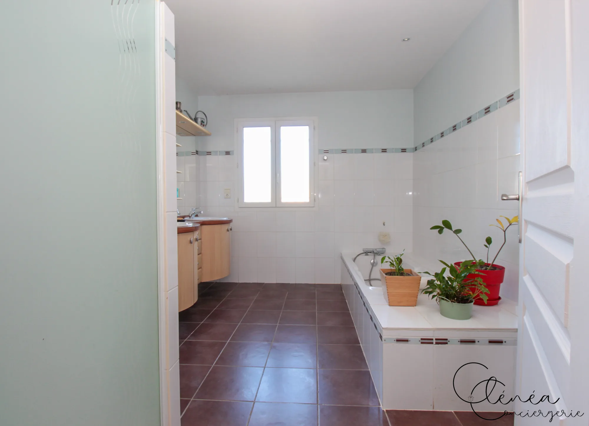 Villa Chanoine — La salle de bain principale en enfilade, avec sa baignoire le long du mur et son meuble double vasque au fond.