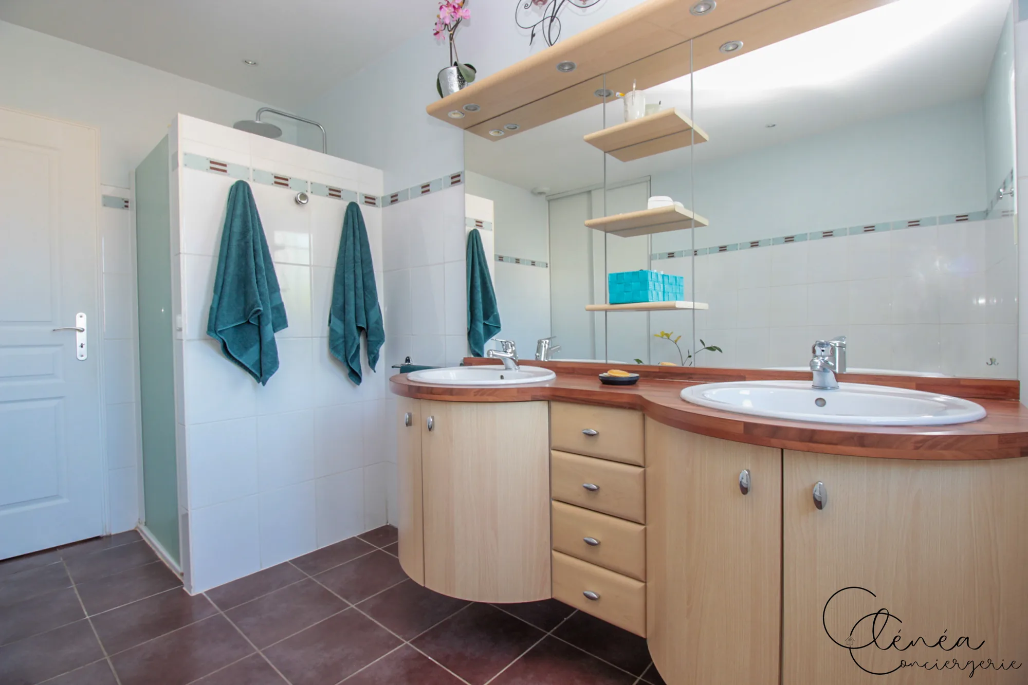 Villa Chanoine — La salle de bain principale avec son meuble double vasque en bois clair, son grand miroir et sa douche.