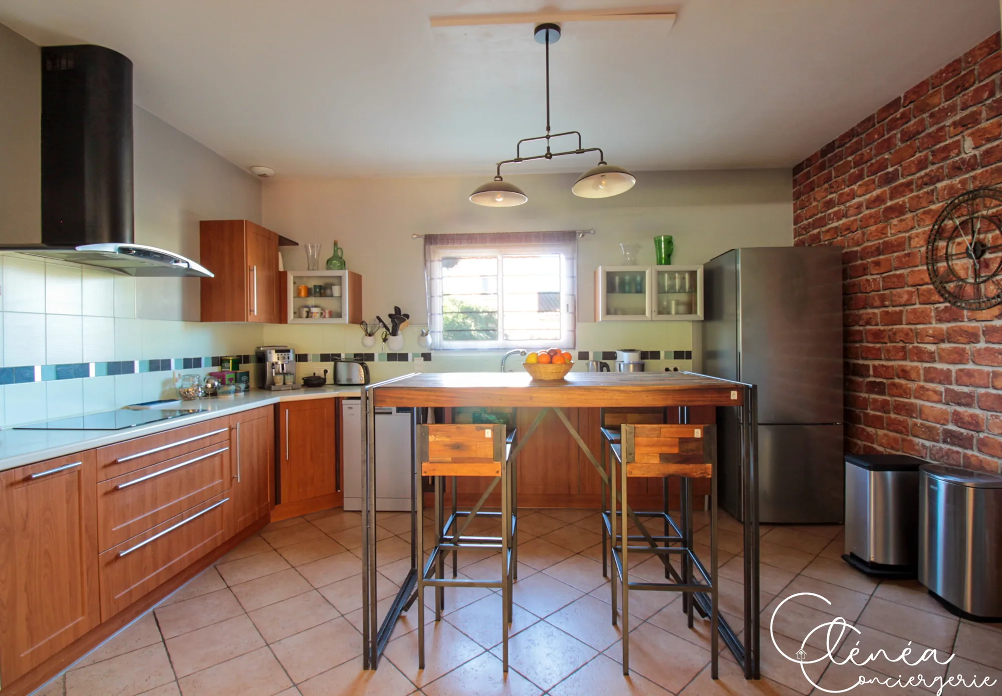 Villa Chanoine — La cuisine vue depuis l'entrée, avec son mur de briques apparentes, son réfrigérateur et sa table haute.